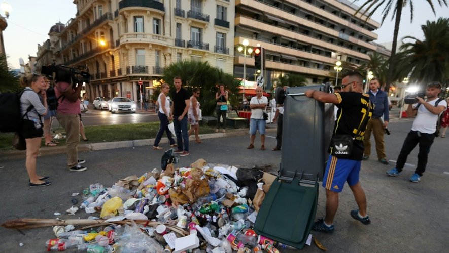 Un homme vide sa poubelle le 18 juillet 2016 à l'endroit où a été tué Mohamed Lahouaiej-Bouhlel, le Tunisien qui a conduit un camion à travers la foule tuant plus de 80 personnes, sur la Promenade des Anglais à Nice