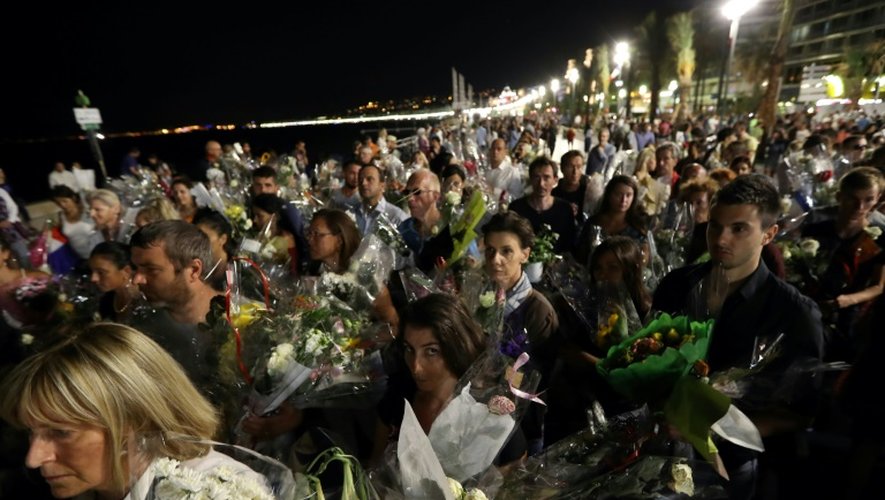 Une chaîne humaine déplace les bouquets déposés sur la Promenade des Anglais en hommage aux victimes de l'attentat du 14 juillet vers le front de mer à Nice le 18 juillet 2016