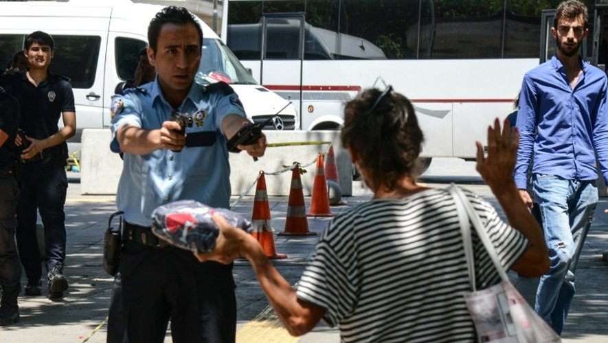 Un policier vise une femme avec son arme pour l'obliger à déposer un paquet qu'elle transporte devant le tribunal d'Ankara le 18 juillet 2016