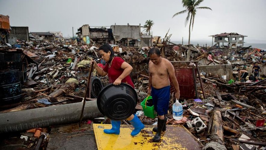 Des habitants de Tacloban se fraient un chemin parmi les débris de maisons détruites, le 22 novembre 2013 aux Philippines