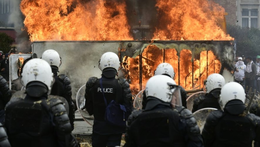 Des policiers face à un feu allumé lors d'une manifestation d'agriculteurs à Bruxelles, le 7 septembre 2015