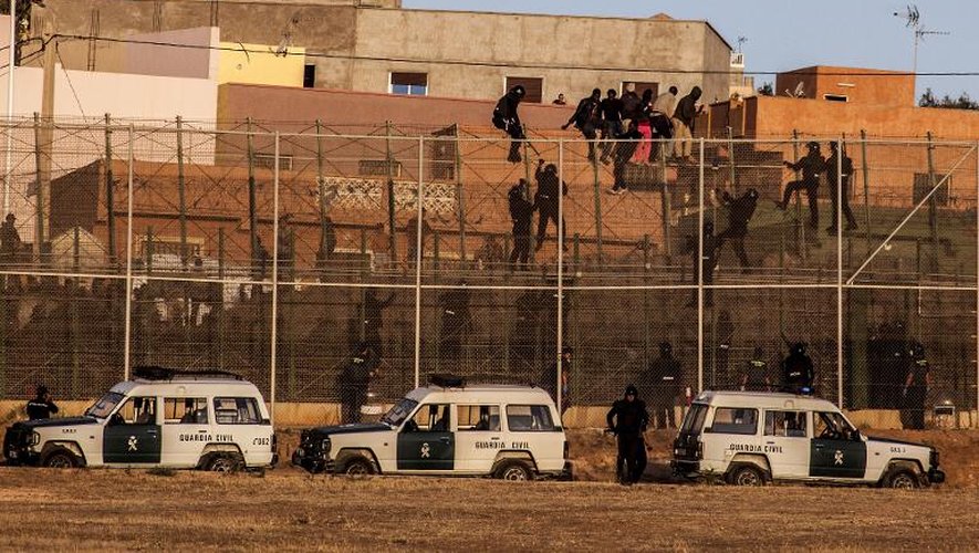 Des membres des garde civile espagnole grimpent sur la barrière, alors que des migrants d'Afrique tentent d'enter dans l'enclave espagnole de Melilla le 14 août 2014