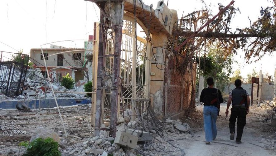 Des rebelles marchent dans les ruines d'immeubles de Mleiha le 25 juillet 2013