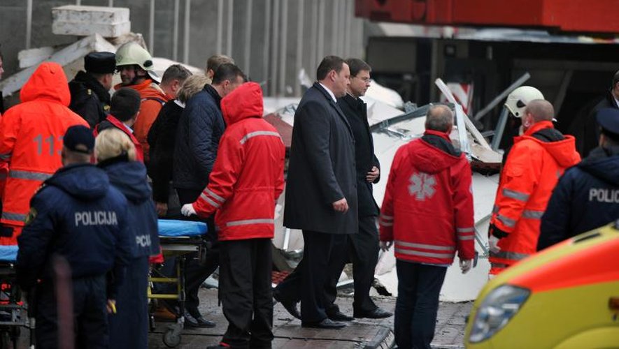 Le Premier ministre de Lettonie, Valdis Dombrovskis (centre d) et le ministre de l'Intérieur Rihards Kozlovskis se rendent sur les lieux de la catastrophe à Riga le 22 novembre 2013