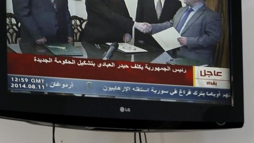 Un journaliste regarde la télévision alors que le président irakien serre la main du nouveau nouveau Premier ministre Haidar al-Abadi le 11 août 2014 à Bagdad