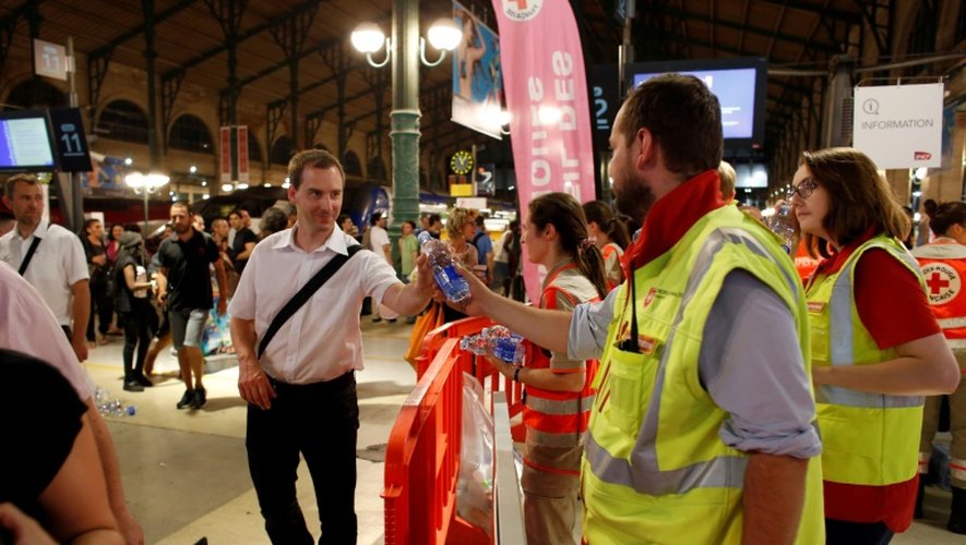 Des membres de la Croix Rouge distribuent de l'eau aux voyageurs coincés dans la soirée à la Gare du Nord, le 19 juillet 2016 à Paris