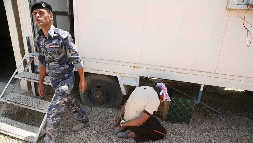 Un membre des forces de sécurité irakienne passe près d'un homme menotté et les yeux bandés après avoir été fait prisonnier le 14 août 2014 à Ramadi