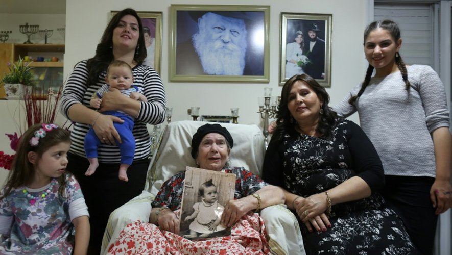 Frecha Amar, 84, pose avec une photo de son bébé qu'elle dit avoir été enlevé en 1958, et sa fille et ses petits-enfants le 29 juin 2016 à Kfar Chabad, près de Tel-Aviv