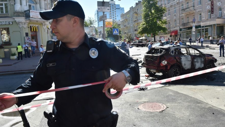 Un policier ukrainien installe un cordon de sécurité sur le lieu de l'explosion de la voiture du journaliste Pavel Cheremet, le 20 juillet 2016 à Kiev