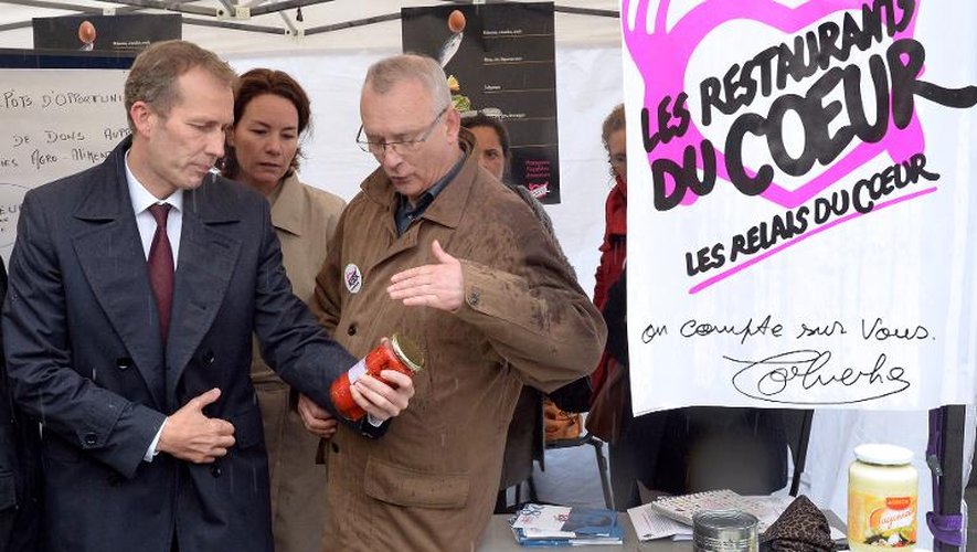 Le ministre délégué chargé de l’Agroalimentaire Guillaume Garot (g) sur un stand des Restos du Coeur à Paris le 16 octobre 2013