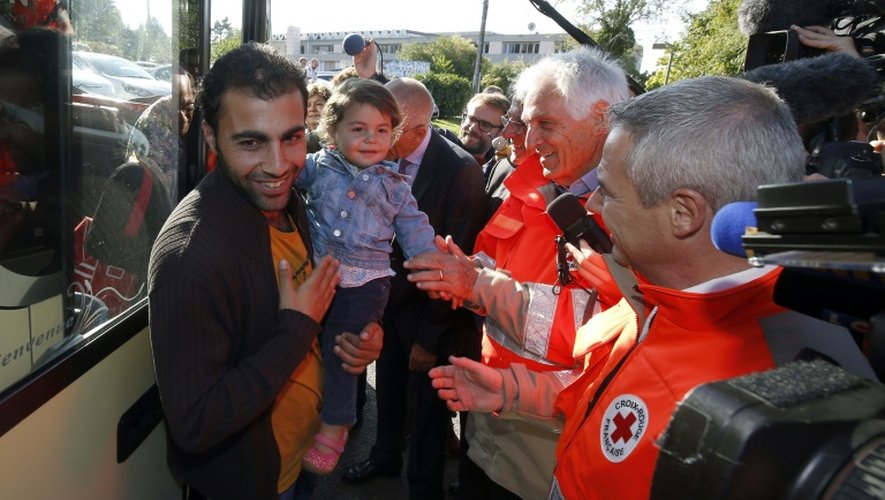 Des réfugiés syriens, érythréens et irakiens arrivant d'Allemagne sont accueillis par le président de la Croix-Rouge française Jean-Jacques Eledjam (2e à d) et des membres de son organisation à Champagne-sur-Seine, en Seine-et-Marne