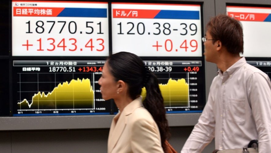 Des passants regardent un tableau d'indices boursiers, le 9 septembre 2015 à Tokyo