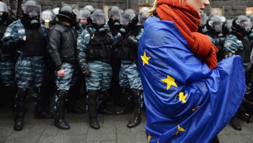 Une manifestante enveloppée du drapeau européen le 25 novembre 2013 devant les forces de l'ordre à Kiev