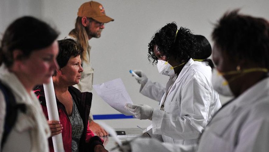 Du personnel médical aide les voyageurs à remplir des formulaires médicaux avant un dépistage du virus Ebola à leur arrivée à l'aéroport international Kenyatta à Nairobi le 14 août 2014