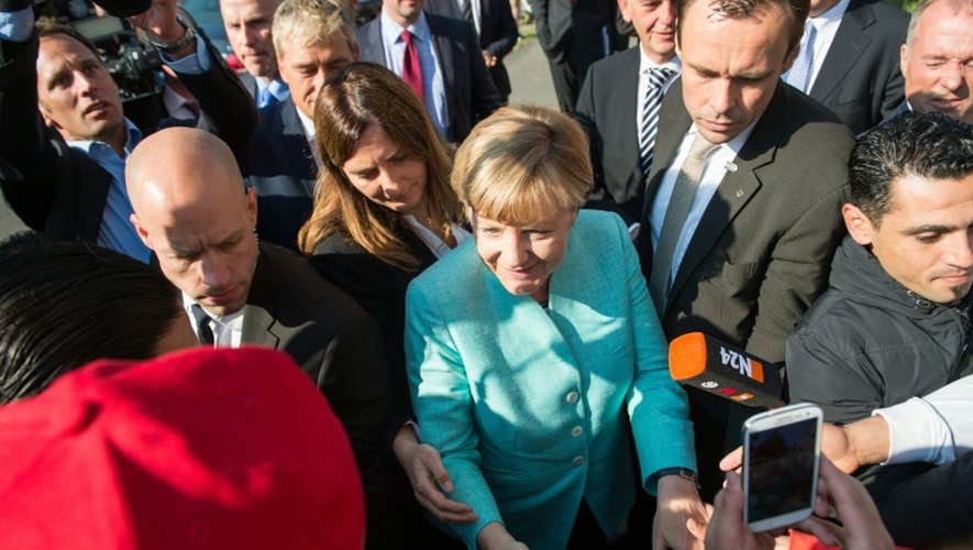 Angela Merkel serre la main de réfugiés alors qu'elle visite un centre d'enregistrement de demandes d'asile, le 10 septembre 2015 à Berlin