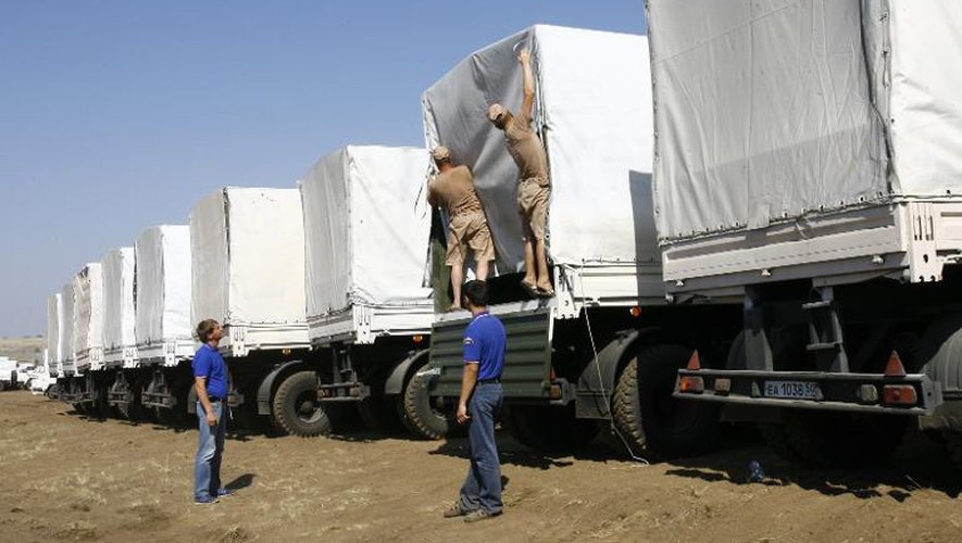 Les chauffeurs russes de camions d'aide humanitaire ouvrent leurs chargement dans un champ près de Kamensk-Shakhtinsky le 15 août 2014