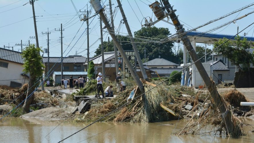 Des habitants au milieu des décombres dans une rue inondée le 11 septembre 2015 à Joso au Japon