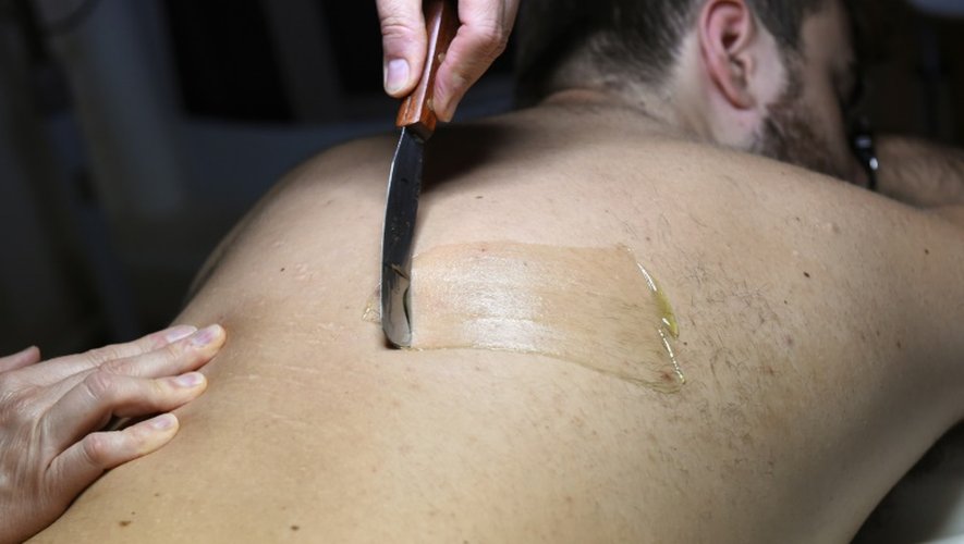 De la cire chaude est appliquée sur le dos d'un jeune homme, lors d'une séance d'épilation dans un salon de beauté parisien, le 4 septembre 2015