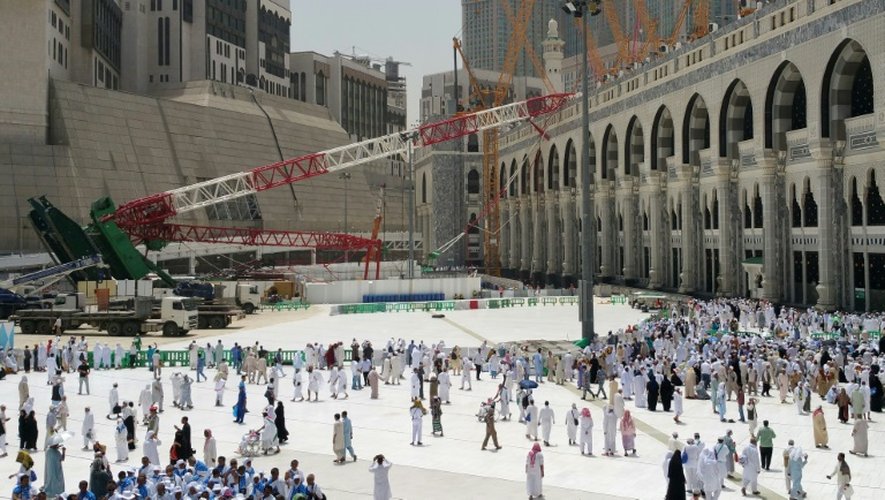 Des saoudiens et des pélerins passent le 12 septembre 2015 devant la grue qui s'est effondrée la veille sur la Grande Mosquée de La Mecque, provoquant la mort de 107 personnes
