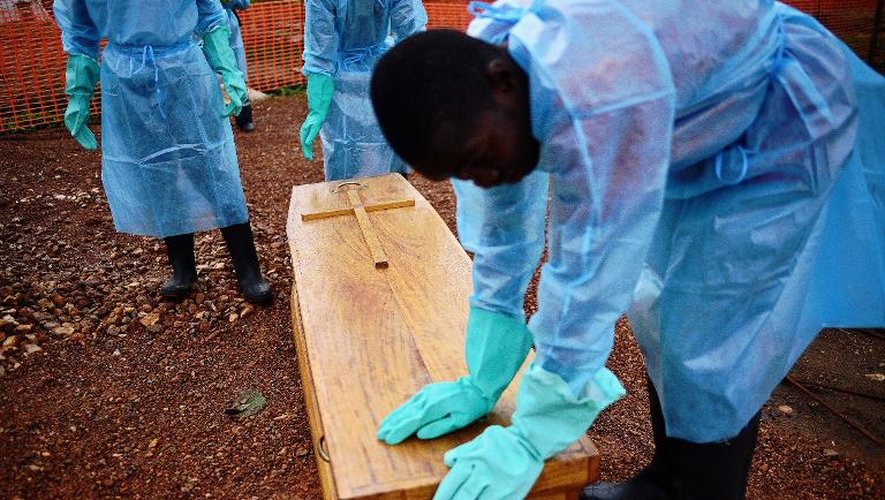 Les personnes chargées de l'enterrement du docteur Modupeh Cole, mort de la fièvre Ebola, se recueillent près de son cercueil, à Kailahun, le 14 août 2014 dans l'est de la Sierra Leone