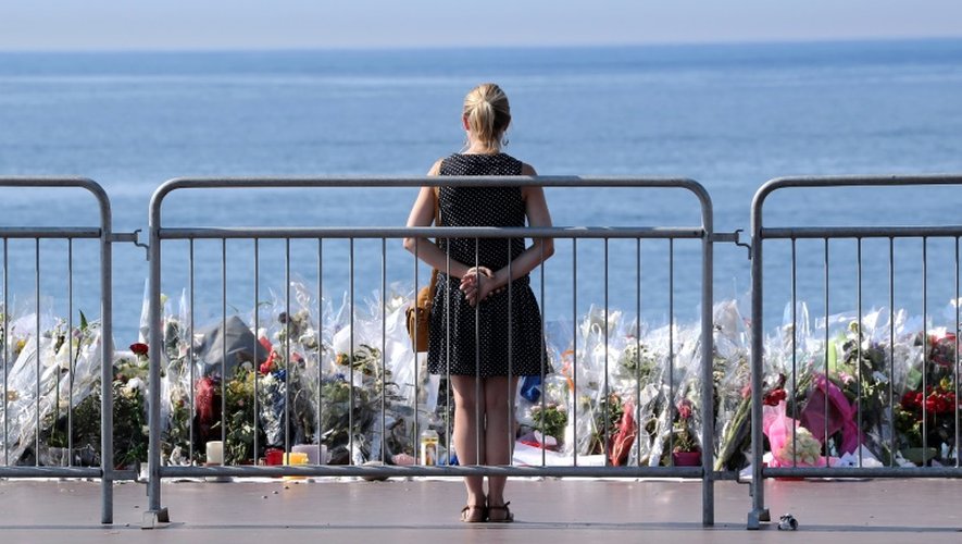 Une femme se tient le 21 juillet 2016 à Nice devant le  trottoir de la Promenade des Anglais qui a été transformé en mémorial