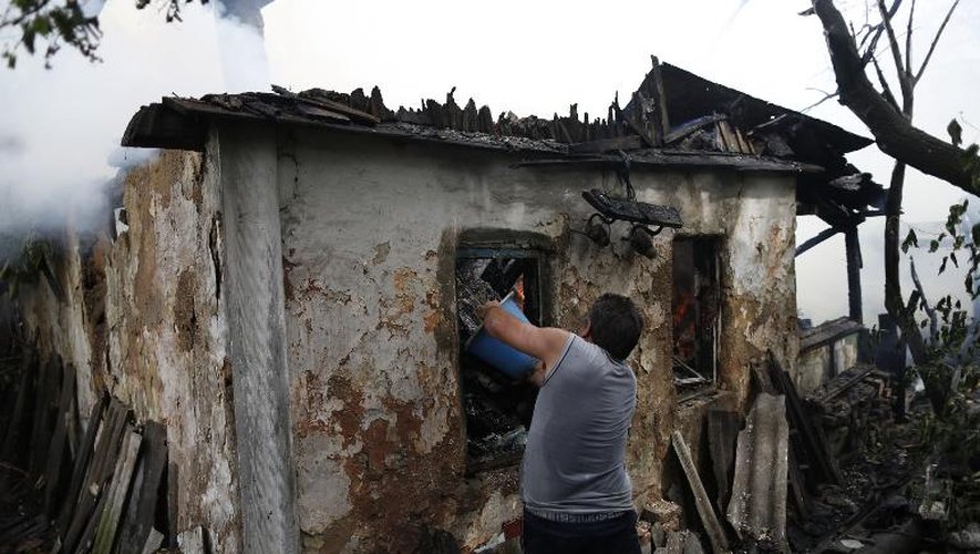 Un homme éteint une maison incendiée le 17 août 2014 dans les faubourgs de Donetsk, place forte des rebelles prorusses dans l'est de l'Ukraine