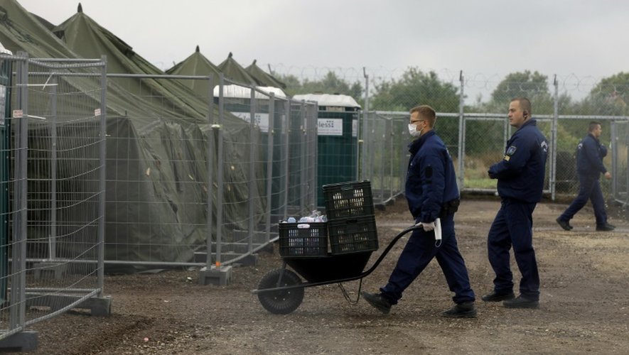 Des policiers apportent des repas dans un camp de réfugiés à la frontière serbo-hongroise, près de Röszke, le 11 septembre 2015 en Hongrie