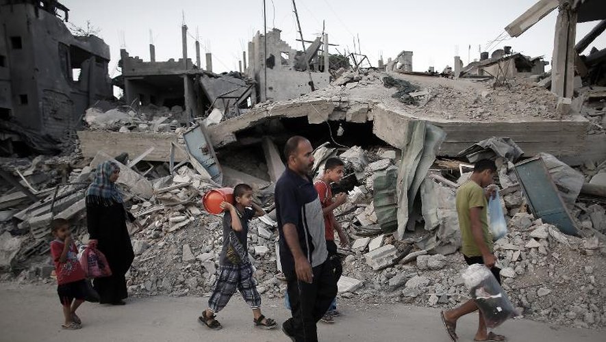 Des familles palestiniennes quittent leurs maisons détruites pour s'abriter dans un bâtiment de l'Onu le 18 juin 2014 à Hanoun dans la Bande de Gaza