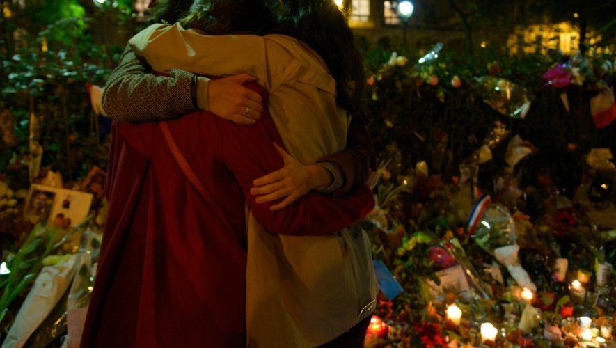 Des gens s'enlacent devant un mémorial en hommage aux victimes de l'attentat du Bataclan, le 20 novembre 2015 à Paris