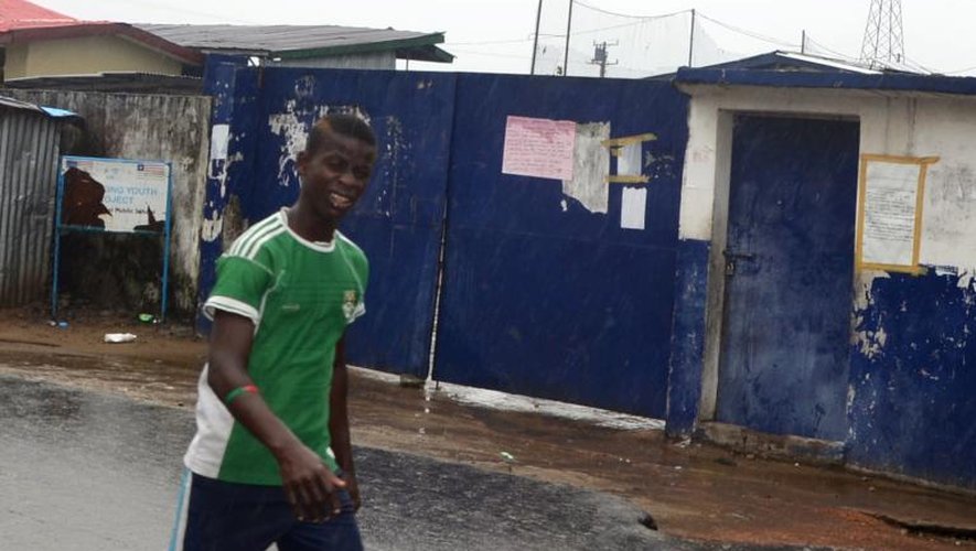 Des passants marchent devant une école transformée en centre d'isolement pour les malades d'Ebola d'où se sont enfuis 17 malades à la suite d'une attaque, le 17 août 2014 à Monrovia au Liberia