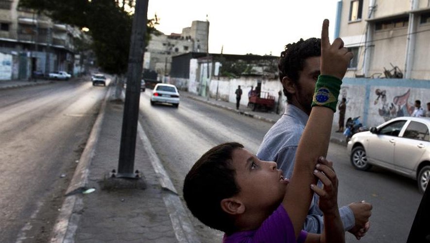 Un garçon palestinien pointe du doigt deux drones israéliens survolant la bande de Gaza en fin d'après-midi le 19 août 2014