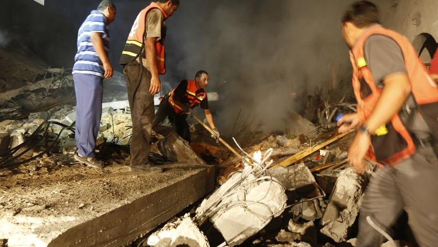 Des Palestiniens dans les ruines d'une maison détruite par un tir israélien le 19 août 2014 à Gasa