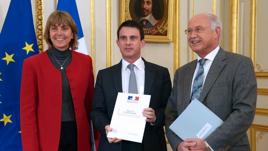 Le ministre de l'Intérieur Manuel Valls entre Valérie Létard et Jean-Louis Touraine, qui lui remettent un rapport sur le système d'asile, à Paris le 28 novembre 2013