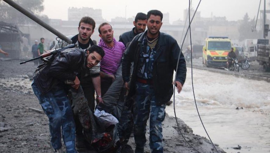 Rebelles et civils syriens portent le corps d'un homme tué dans un bombardement à Alep, le 28 novembre 2013