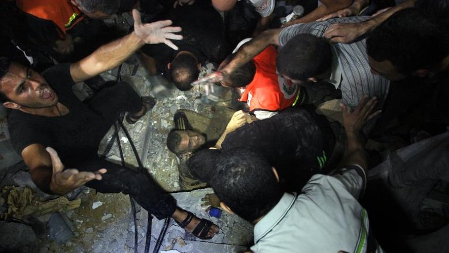 Des secouristes tentent d'extraire des décombres de sa maison un Palestinien blessé le 19 août 2014 à Gaza