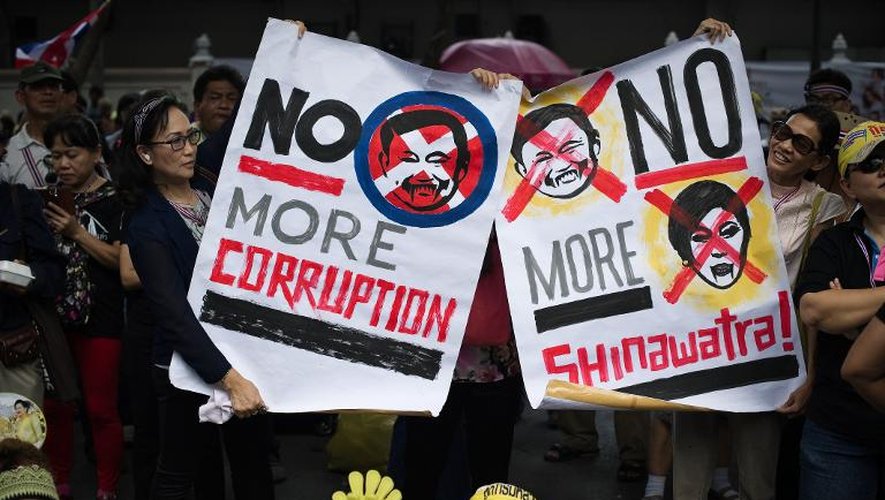 Des manifestants contre le gouvernement tiennent des pancartes avec les portraits de la Première ministre Yingluck Shinawatra et de l'ex-Premier ministre Thaksin Shinawatra, le 28 novembre 2013 devant le siège de la police nationale à Bangkok