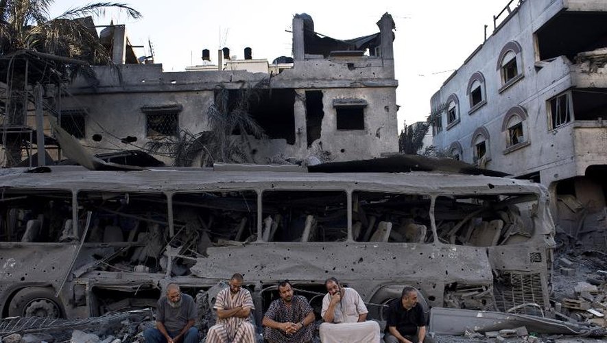 Des Palestiniens devant un bâtiment détruit par un raid israélien à Gaza, le 20 août 2014
