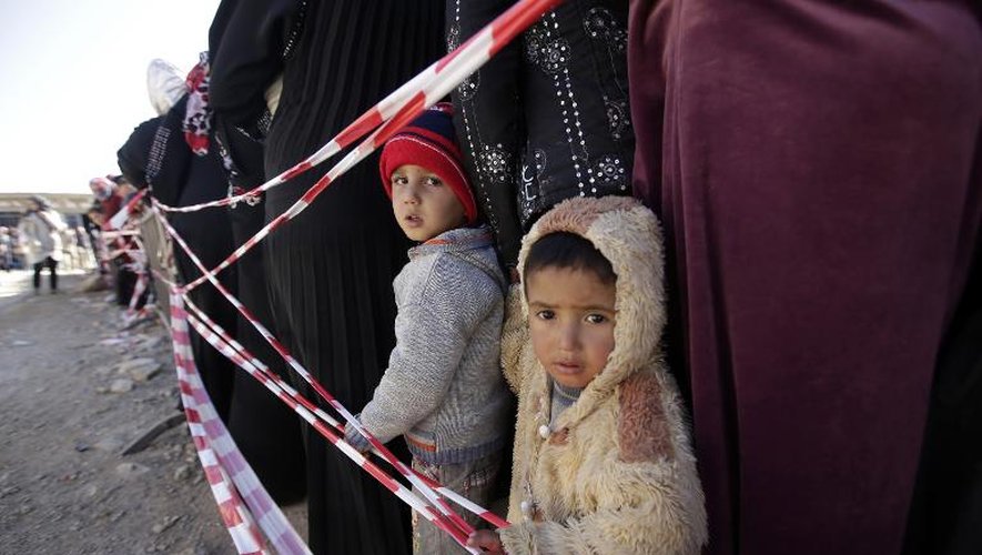 Des enfants réfugiés syriens attendent avec leurs parents pour être enregistrés dans un camp du HCR à Arsal, dans la vallée de la Békaa, au Liban, le 19 novembre 2013