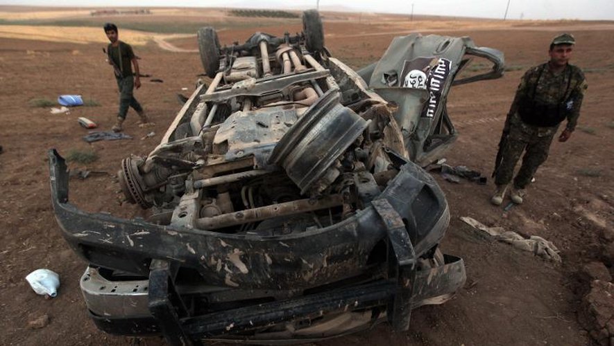 Des peshmergas inspectent l'épave d'un véhicule aux couleurs de l'Etat islamique, détruit par une frappe américaine, à Baqufa au nord de Mossoul, le 18 août 2014 en Iraq