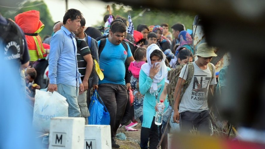 Des migrants sont surveillés par la police hongroise, à la frontière entre la Serbie et la Hongrie, le 14 septembre 2015
