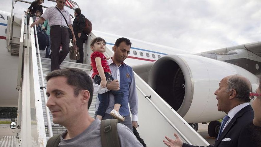 Des réfugiés irakiens chrétiens à leur arrivée à Paris le 21 aout 2014, accueillis par le ministre des Affaires étrangères Laurent Fabius