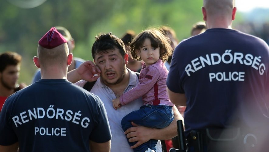 Bloqué par des policiers hongrois,un migrant essuie ses larmes le 14 septembre 2015 près de Roszke à la frontière entre la Hongrie et la Serbie