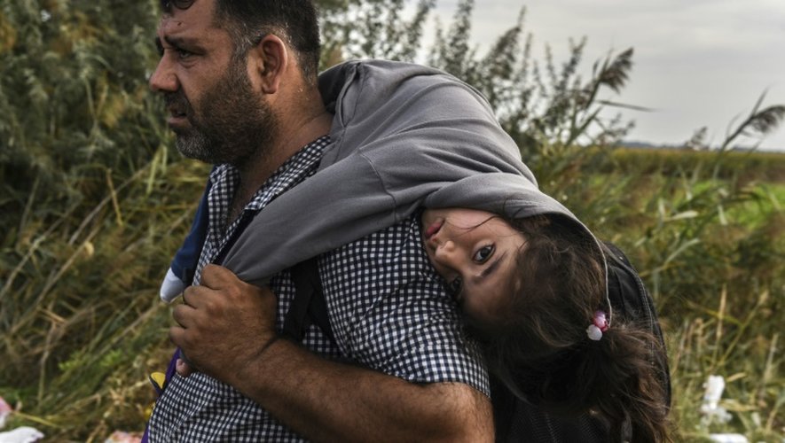 Un réfugié sa fille sur le dos le 14 septembre 2015 à Horgos en Serbie àla frontière avec la Hongrie