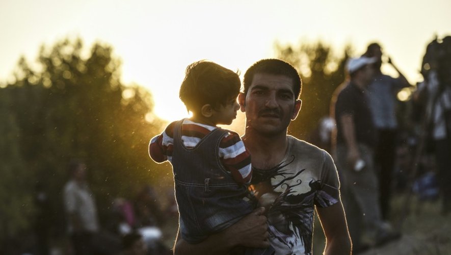 Un migrant syrien porte son enfant sur le chemin qui les conduit à la frontière entre la Turquie et la Bulgarie, le 15 septembre 2015, à Edirne