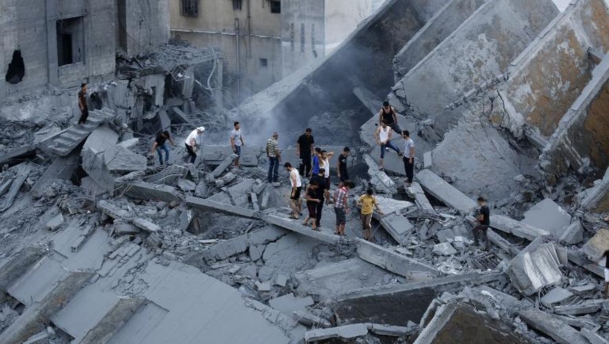 Des Palestiniens inspectent les restes d'un immeuble détruit par une attaque israélienne à Gaza, le 26 août 2014