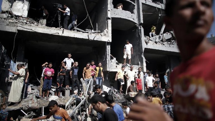 Des Palestiniens rassemblés dans les décombres d'un immeuble détruit après une attaque israélienne à Rafah, dans le sud de la bande de Gaza, le 21 août 2014