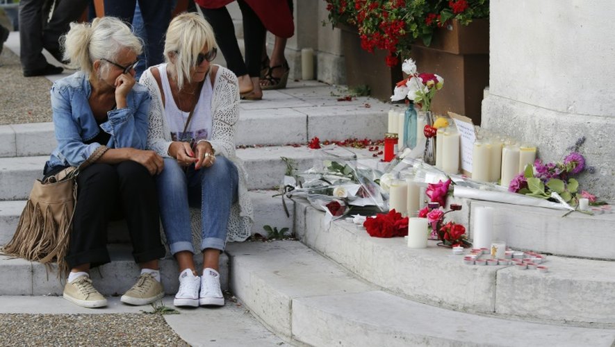 Deux femmes à l'entrée de la mairie où sont déposées fleurs et bougies en hommage au père Jacques Hamel, le 26 juillet 2016 à  Saint-Etienne du Rouvray