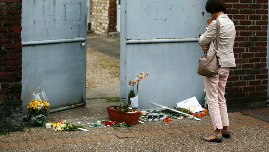 Une femme se recueille devant le domicile du père Jacques Hamel le 27 juillet 2016 à Saint-Etienne-du-Rouvray