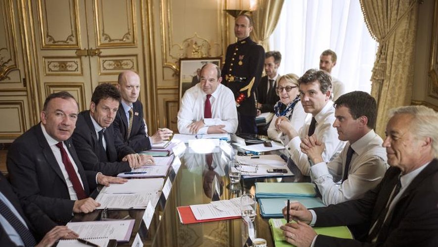 Photo du 11 avril 2014 montrant le Premier ministre Manuel Valls (gauche) entouré de ses ministres, face au patron des patrons Pierre Gattaz (d) et au vice-président du Medef Geoffroy Roux de Bezieux à Matignon