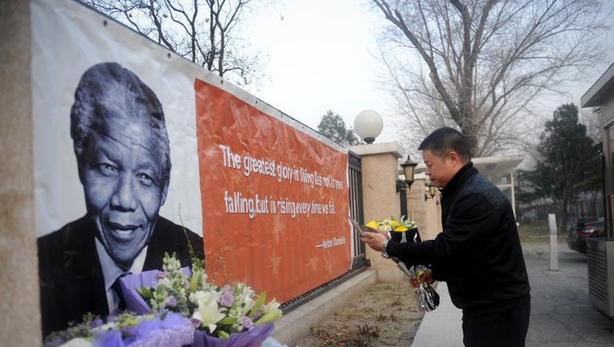 Un homme dépose des fleurs devant l'ambassade d'Afrique du Sud à Pékin, le 6 décembre 2013